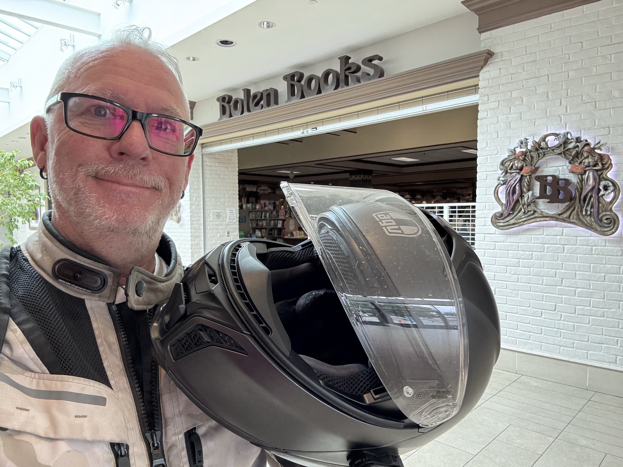 Michael Dargie holding a motorcycle helmet outside Bolen Books on the BrandJitsu™ BC Book Tour