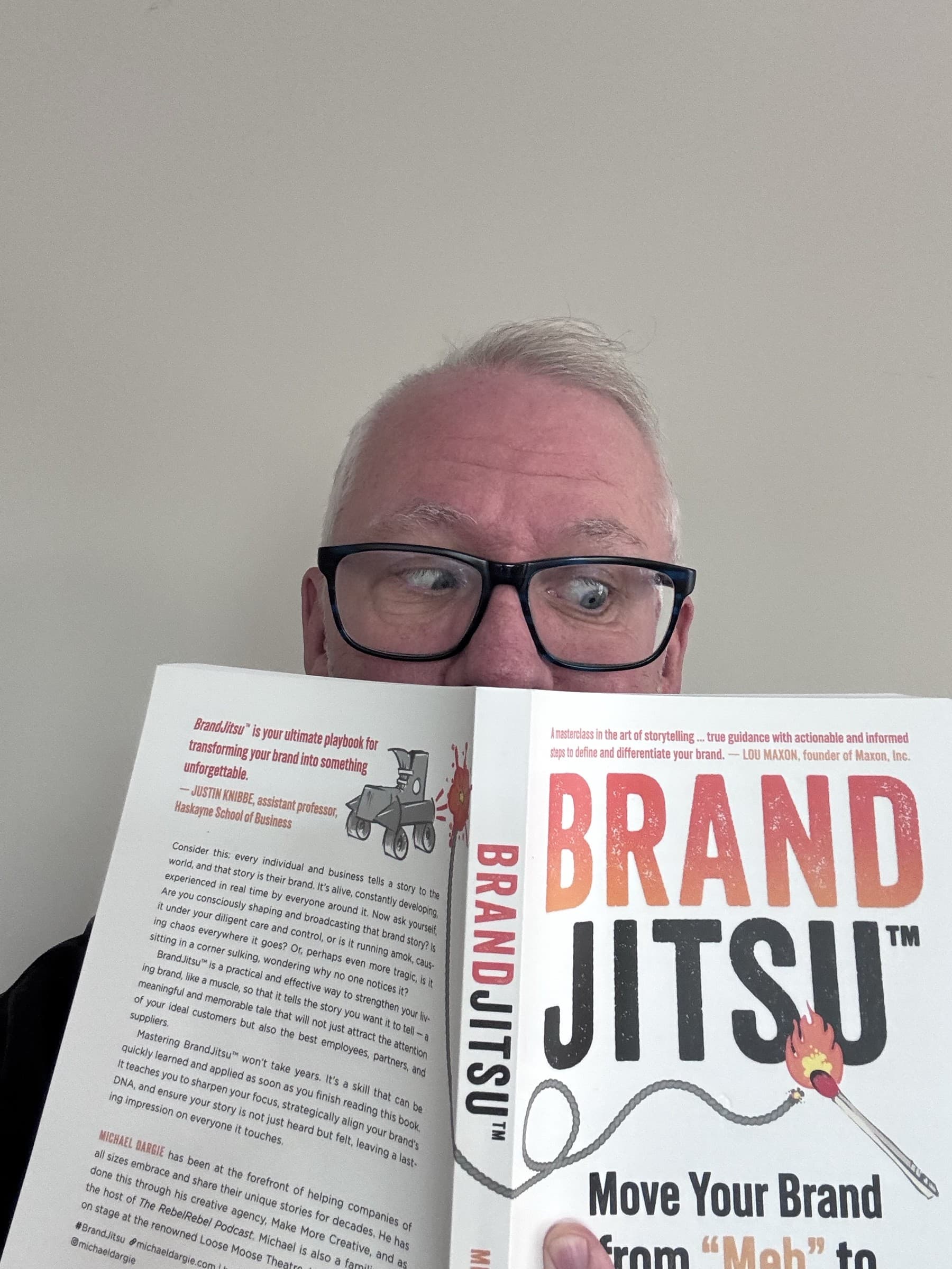 Michael Dargie holding the BrandJitsu™ book up to his face, reading his own work